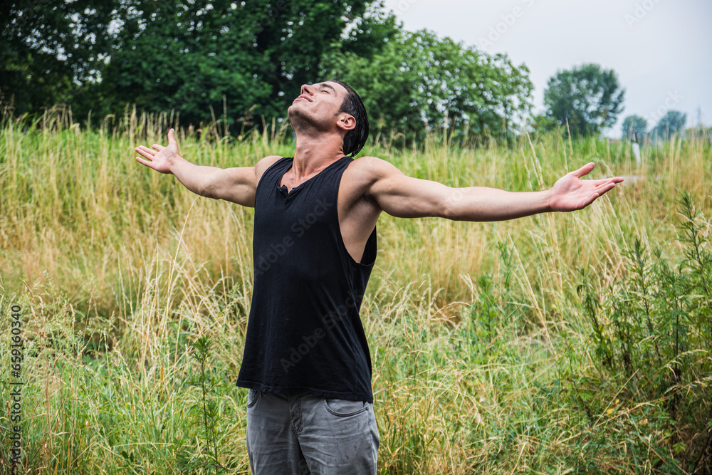 A man standing in a field with his arms outstretched. Photo of a man standing in a field with his arms outstretched in a freedom or liberation concept A man standing in a field with his arms outstretched. Photo of a man standing in a field with his arms outstretched in a freedom or liberation concept
