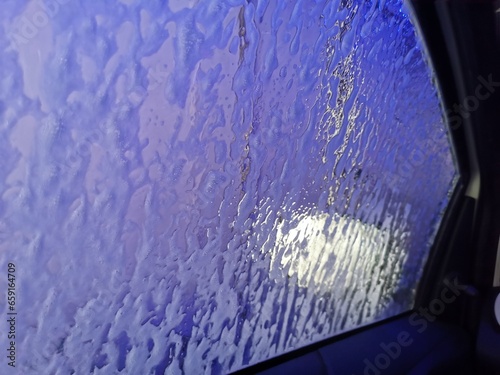 Automatic Car Wash Process. Spray foam bubble shampoo on the car surface. Car wash view from the salon