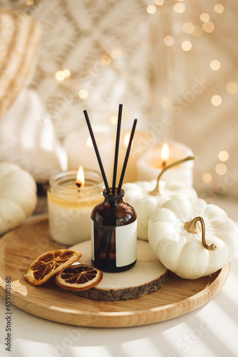 Cozy corner for home meditation and relaxation. Fall aroma diffuser with pumpkin pie scent, cinnamon, orange, burning candles for comfort, pleasure, aromatherapy. Apartment decor, house design photo