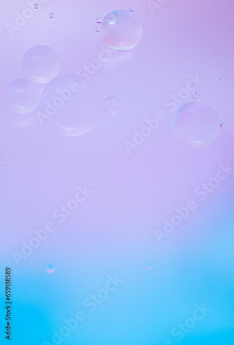 Abstract background in blue and lilac soft tones. Macro drops of oil on the surface of the water. Delicate cosmetic background for advertising products. Vertical photo