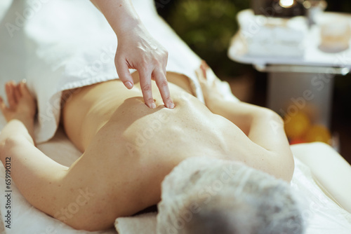 Closeup on medical massage therapist massaging clients back