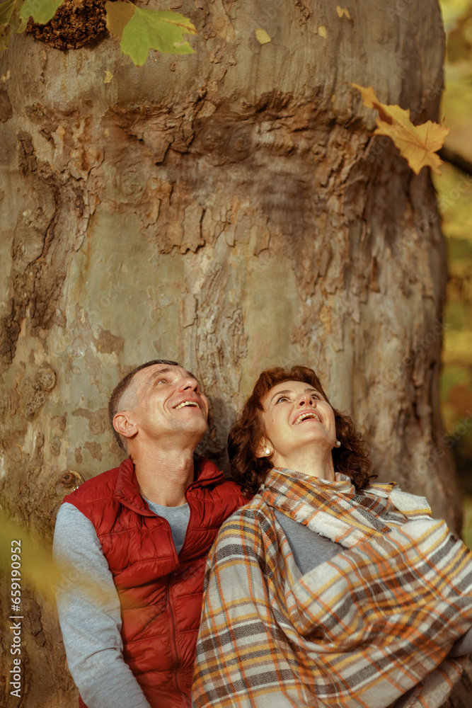 smiling modern couple in park near tree