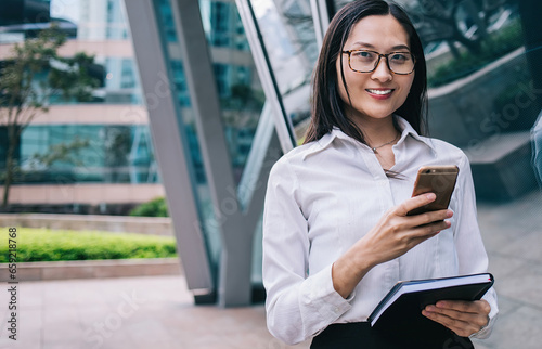 Cheerful woman browsing smartphone on street