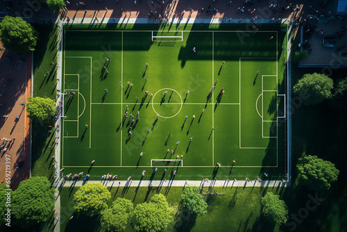 Aerial view of people on a university sports lawn, top down view of an American soccer pitch with students, grass on the field greenery and trees all around, drone view  photo