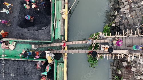 Coal workers in Dhaka city, Bangladesh, unload coal from barges in a scene that highlights the challenges and resilience of manual labor in a developing country.