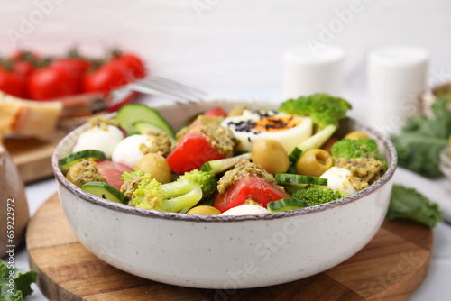Delicious salad with pesto sauce in bowl on table, closeup