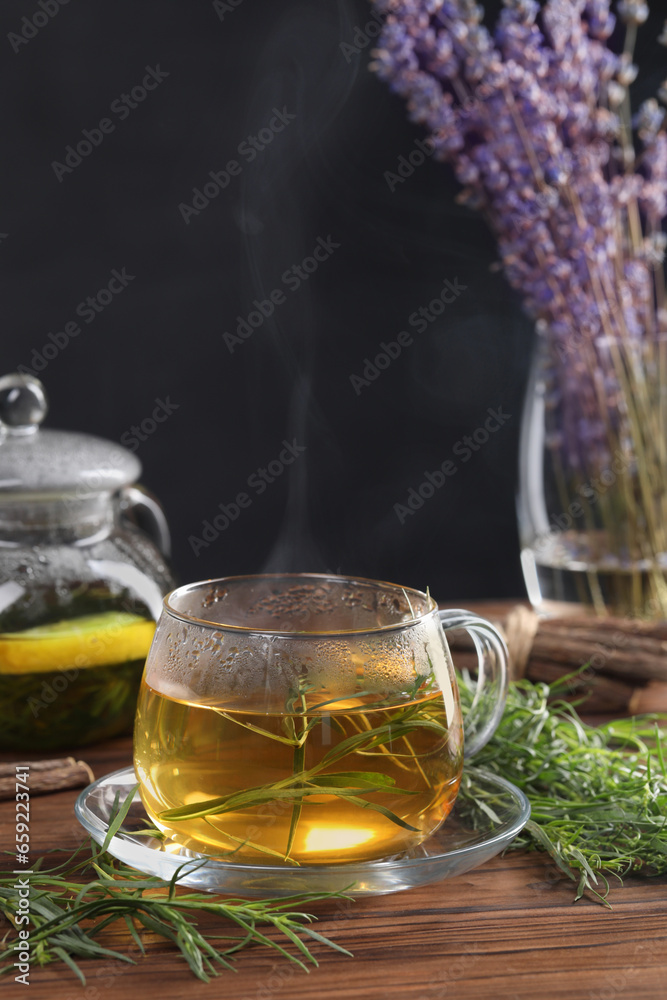 Homemade herbal tea and fresh tarragon leaves on wooden table Homemade herbal tea and fresh tarragon leaves on wooden table