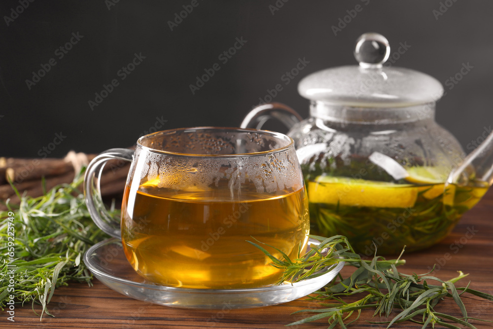Homemade herbal tea and fresh tarragon leaves on wooden table Homemade herbal tea and fresh tarragon leaves on wooden table