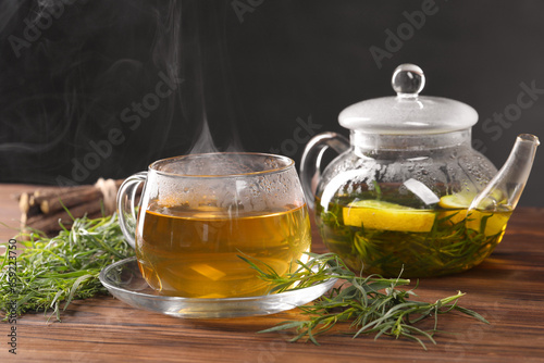 Homemade herbal tea and fresh tarragon leaves on wooden table