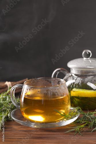 Homemade herbal tea and fresh tarragon leaves on wooden table