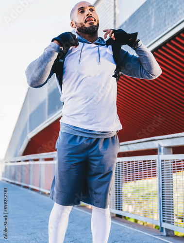 Athletic African American man fixing backpack