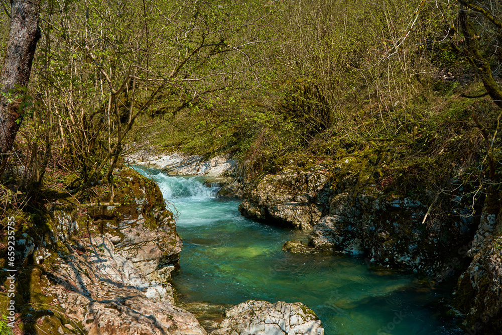 The natural pool of the mountain river with emerald clear water