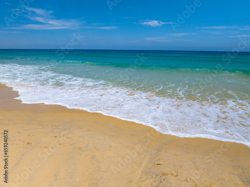 Aerial view of Waves crashing on sandy shore in sunny day,Sea surface ocean waves background,Top view beach background,Phuket Thailand