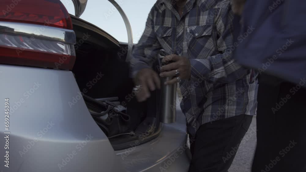 Two old person prepare for hiking they put them stuff in trunk of a car Two old person prepare for hiking they put them stuff in trunk of a car