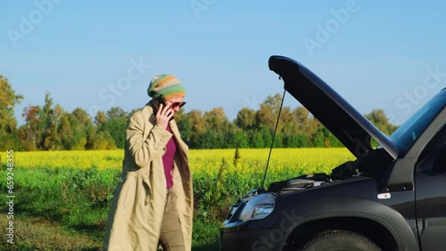 Woman driver calling roadside assistance for help with her car trouble. Car breakdown drove into a ditch in a deserted countryside. photo