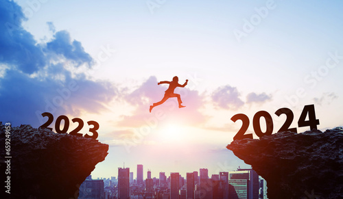 Silhouette of businessman jumping from 2023 to 2024. 2024 New Year concept. New year's card 2024. Wide angle visual for banners or advertisements.