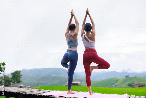 young girls is doing yoga training on balcony of resort with rice terraces, Ban Pa Bong Piang and mountains green over white sky in rainy season, Travel healthy lifestyle,