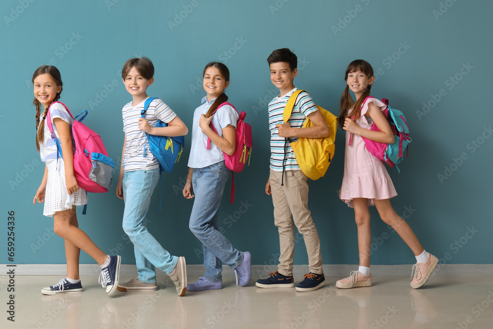 Obraz premium Little pupils with backpacks near blue wall