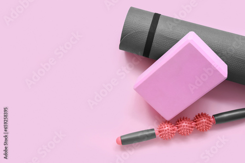 Fototapeta Naklejka Na Ścianę i Meble -  Yoga mat, foam exercise block and massage roller on pink background