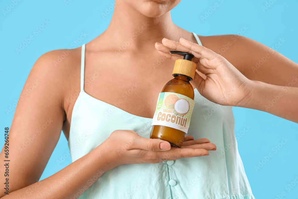 Beautiful young woman with coconut oil on blue background, closeup Beautiful young woman with coconut oil on blue background, closeup