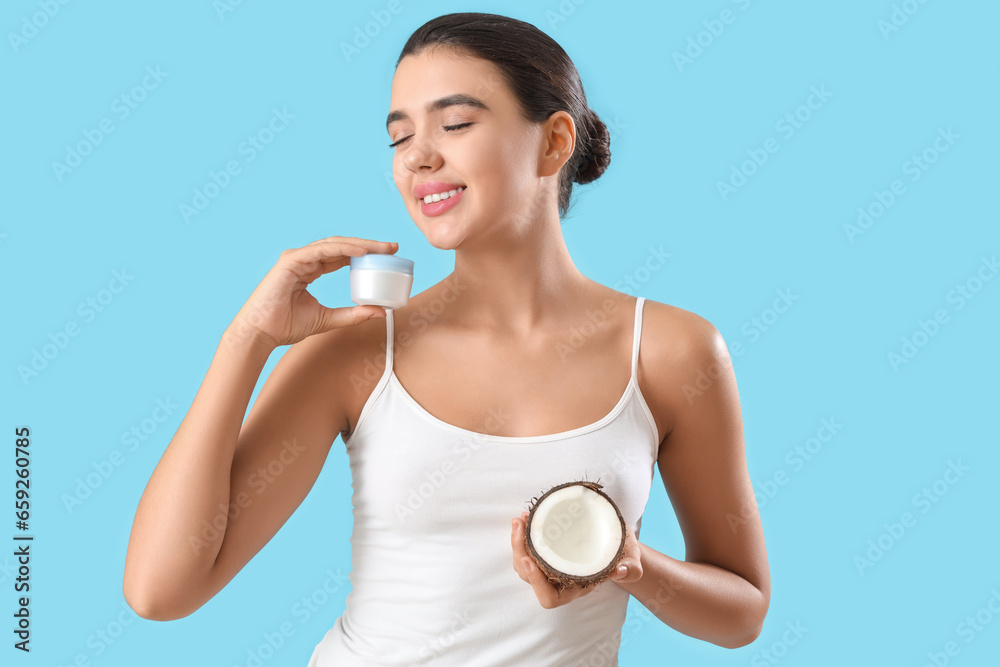 Pretty young woman with cream and coconut on blue background Pretty young woman with cream and coconut on blue background