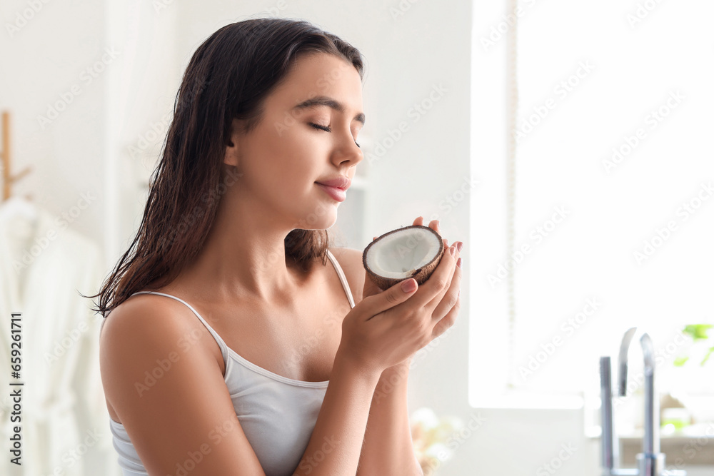 Pretty young woman with coconut in bathroom. Skin care concept Pretty young woman with coconut in bathroom. Skin care concept