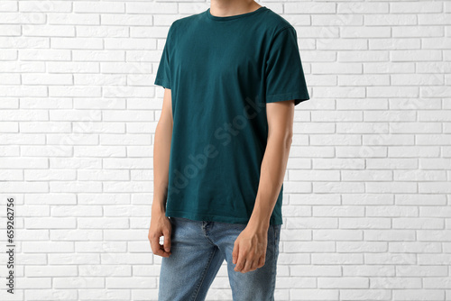 Man in stylish t-shirt near white brick wall