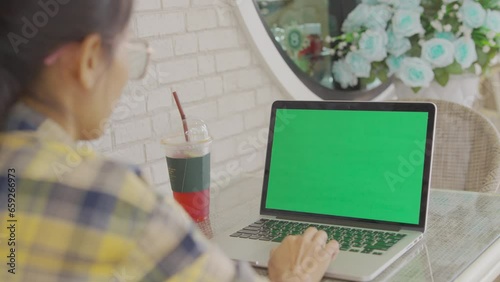 Over the shoulder shot of woman, using finger with keyboard for typing touch. computer laptop with blank green screen chroma key in cafe.