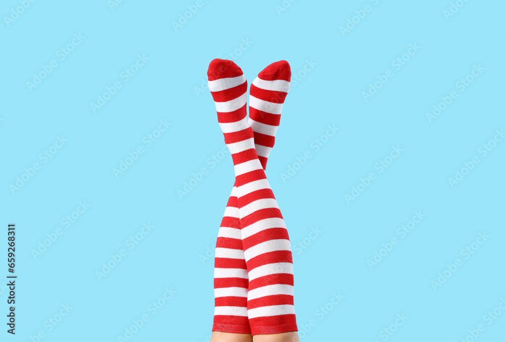 Female legs in Christmas stockings on blue background Female legs in Christmas stockings on blue background
