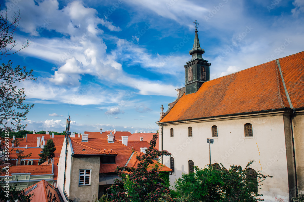 Petrovaradin is historic town on right bank of Danube in Serbia, part of Novi Sad.  Top view of the tiled orange roofs with white chimneys and magic cloudy sky