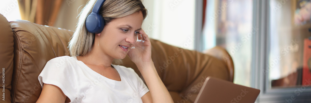 Naklejka premium Woman works on laptop and listens to music in headphones