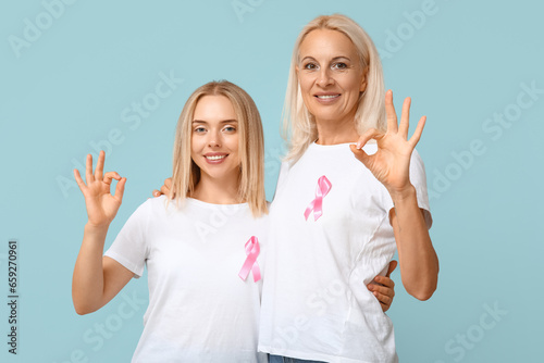 Women with pink ribbons showing OK on blue background. Breast cancer awareness concept