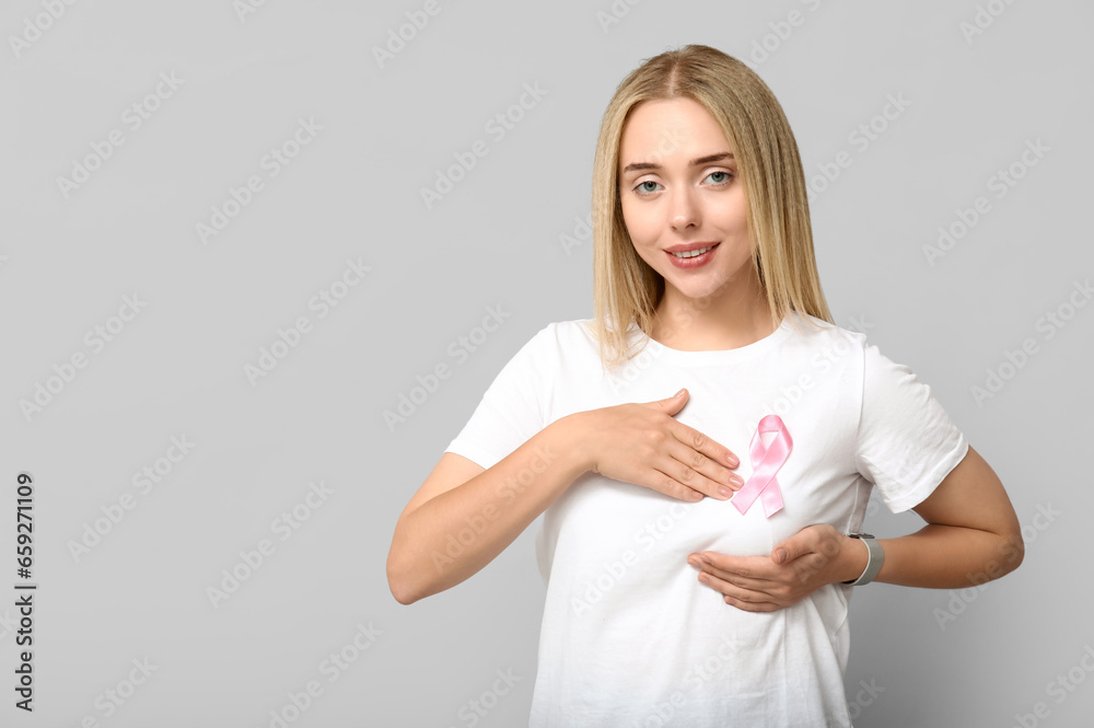 Young woman with pink ribbon on grey background. Breast cancer awareness concept Young woman with pink ribbon on grey background. Breast cancer awareness concept