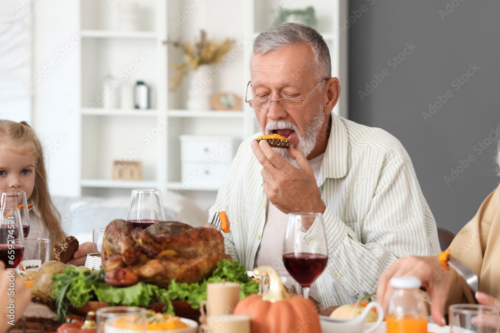 Mature man having family dinner at festive table on Thanksgiving Day Mature man having family dinner at festive table on Thanksgiving Day