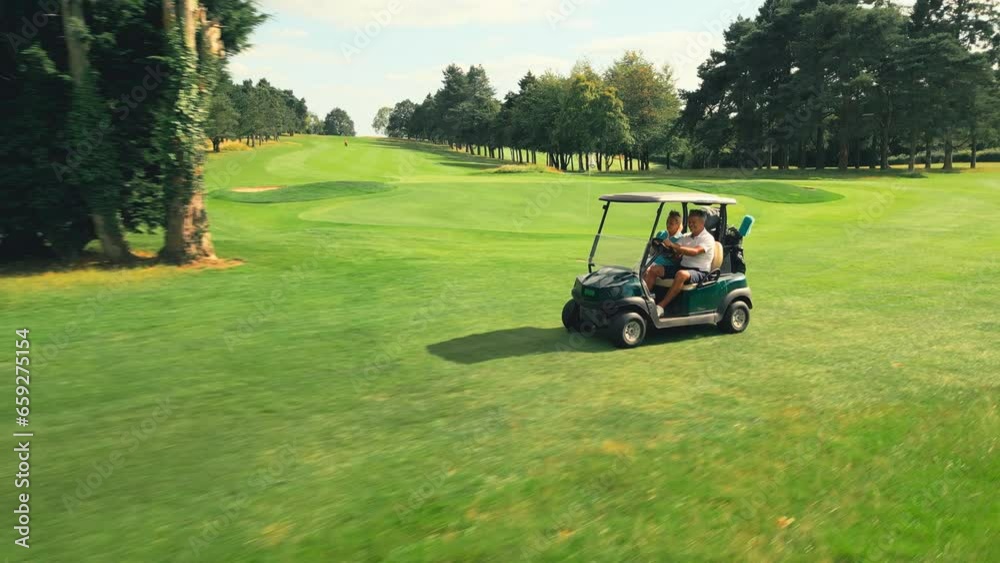 Drone shot of senior retired couple riding in golf buggy on course- shot in slow motion Drone shot of senior retired couple riding in golf buggy on course- shot in slow motion