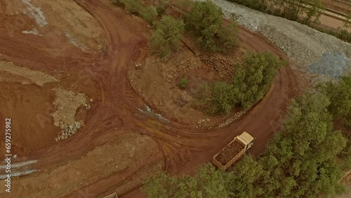 Low aerial view of dump trucks moving tonnes of Nickel rich ore around a mining site in Taganito. photo