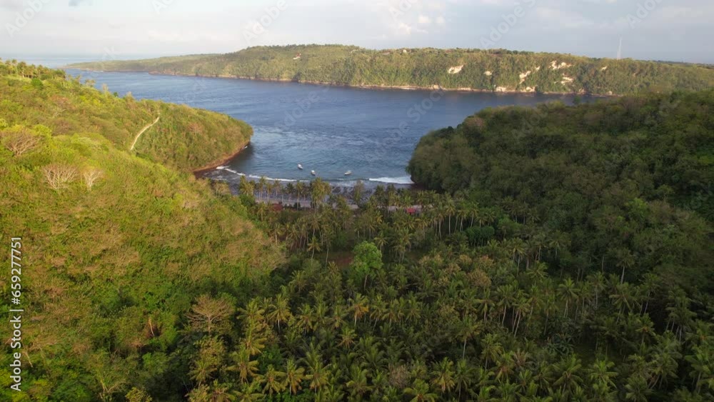 Aerial Sunrise Flying Over Hilly Tropical Forest Revealing Gamat Bay Beach in Nusa Penida, Bali, Indonesia Aerial Sunrise Flying Over Hilly Tropical Forest Revealing Gamat Bay Beach in Nusa Penida, Bali, Indonesia