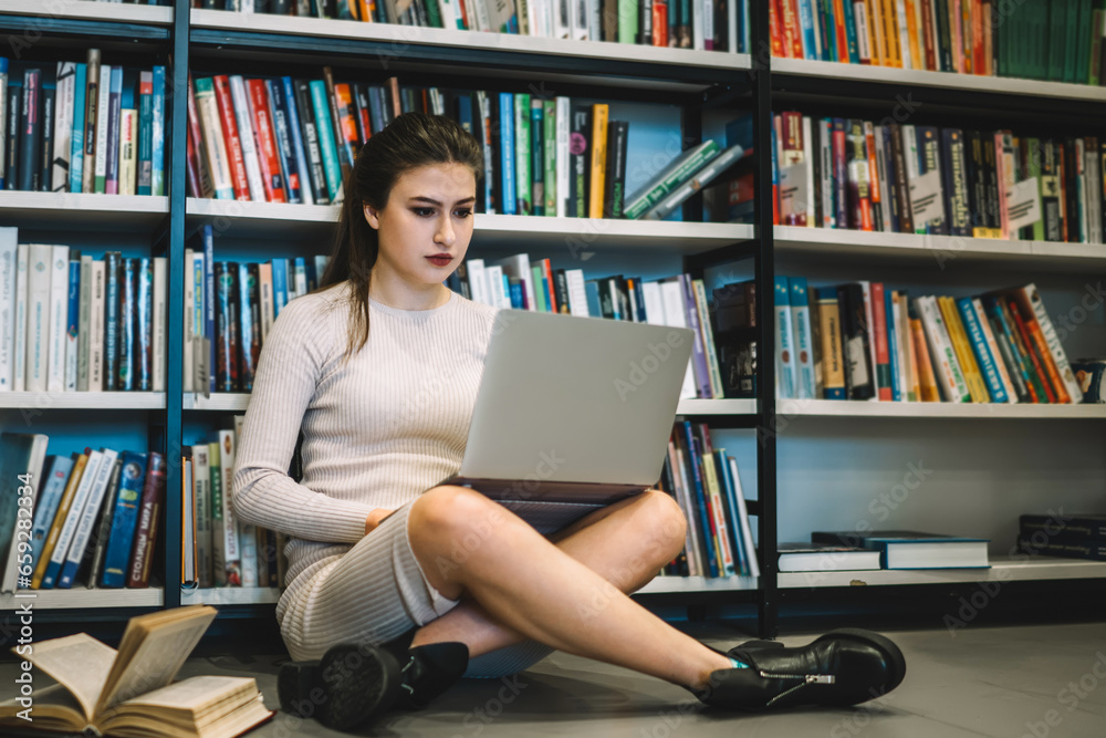 Serious smart woman working on laptop in library Serious smart woman working on laptop in library