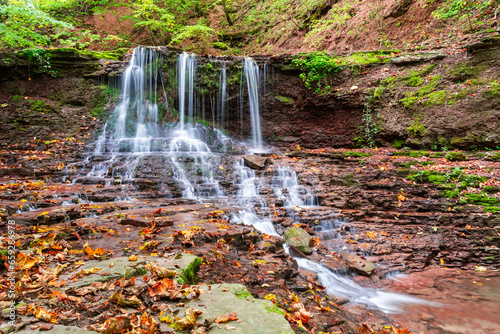 Beautiful waterfall in a mountain stream in the forest. One of the waterfalls of the cascade of Rusiliv waterfalls. Rusyliv, Ternopil Region, Ukraine photo