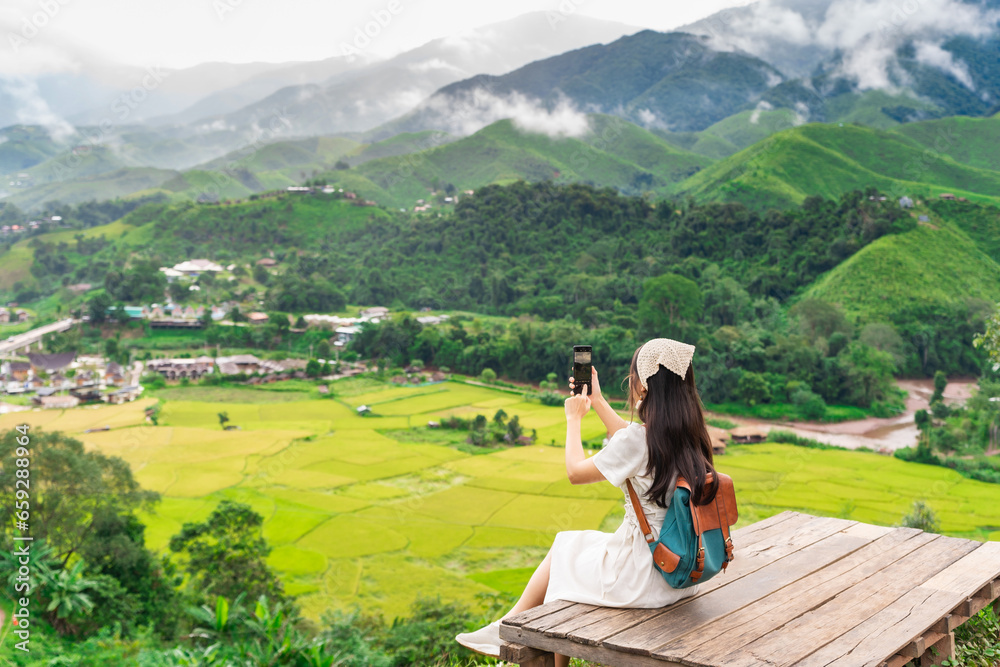 Naklejka premium Young happy woman tourist enjoying and relaxing with beautiful landscape view rice paddy field while traveling at Nan, Thailand