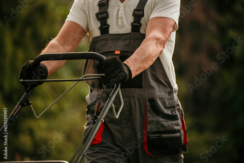 Senior man in work attire diligently mowing his backyard lawn on a sunny day