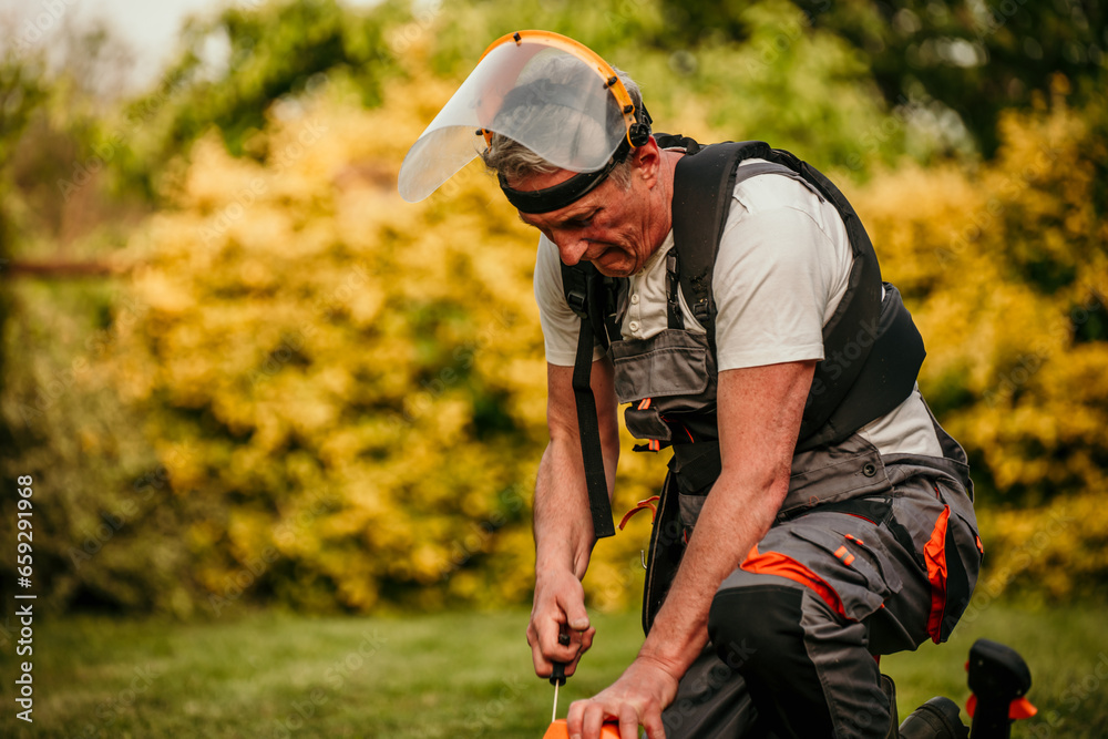 Experienced senior landscaper with a trimmer, about to transform his overgrown backyard Experienced senior landscaper with a trimmer, about to transform his overgrown backyard