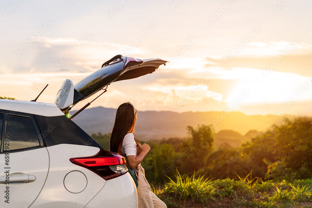 Young woman traveler with car watching a beautiful sunrise over the mountain while traveling road trip on vacation, Travel concept - obrazy, fototapety, plakaty 