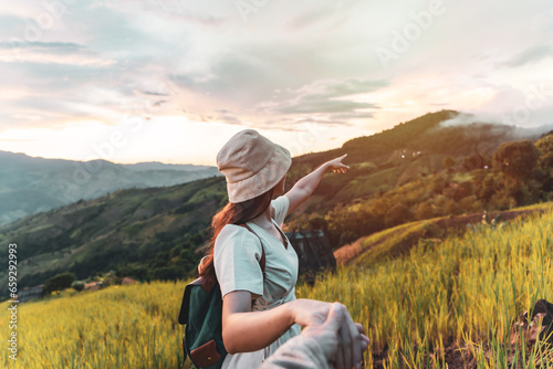 Happy young couple traveler relaxing and looking at the beautiful sunrise on the top of mountains, Travel lifestyle concept