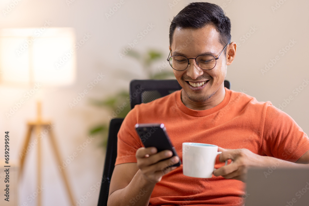 Picture of young asian man using a smartphone and smiling. working at home.accountant Documents data contract report for analysis TAX. Picture of young asian man using a smartphone and smiling. working at home.accountant Documents data contract report for analysis TAX.
