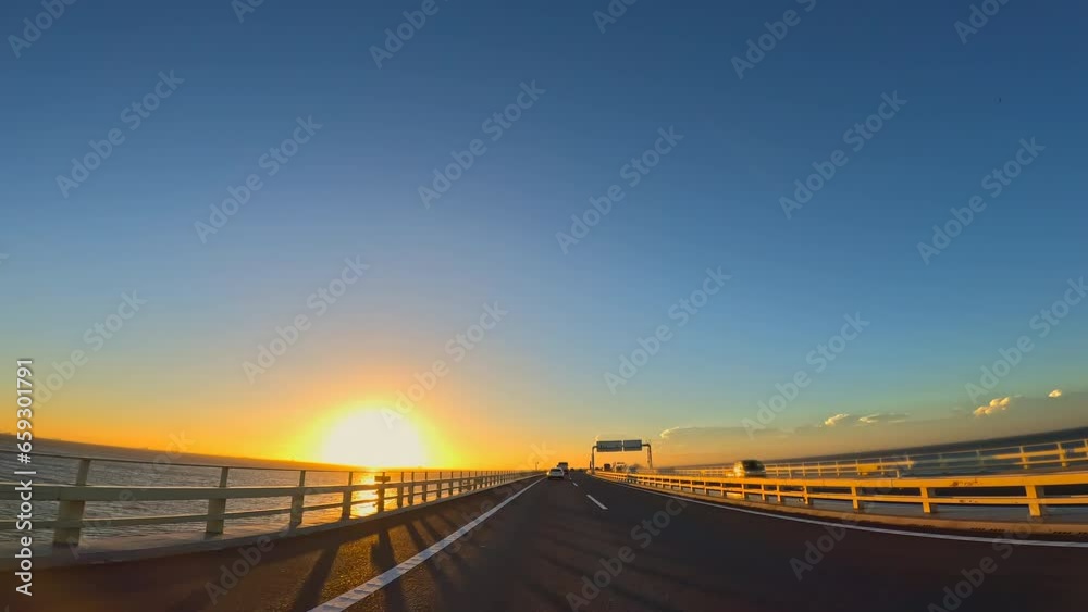 夕暮れの海の上の高速道路を走る自動車