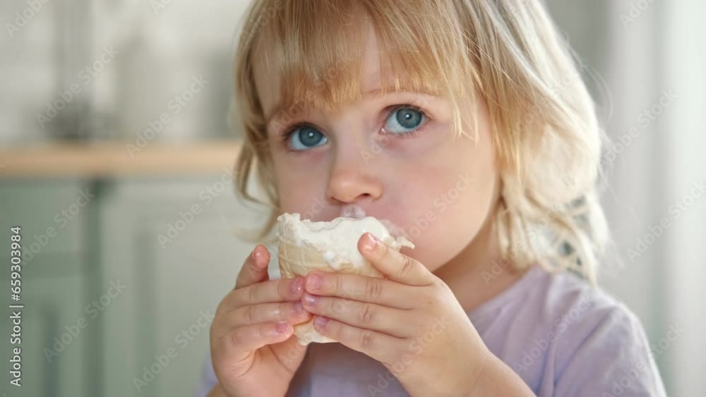 Baby girl enjoying ice cream. Pretty little toddler eating an ice-cream indoors, at home. Dining room background. Small child eats plombir and cream messy on her mouth. Cute kid with tasty sweet food. Baby girl enjoying ice cream. Pretty little toddler eating an ice-cream indoors, at home. Dining room background. Small child eats plombir and cream messy on her mouth. Cute kid with tasty sweet food.