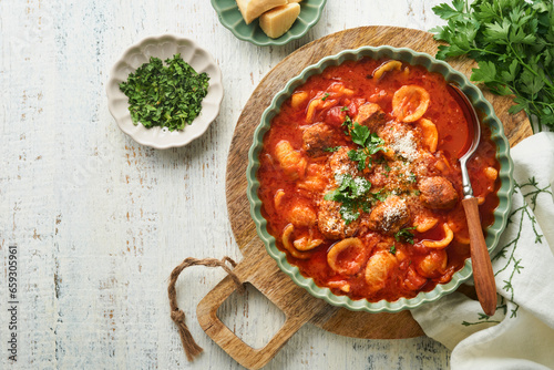 Soup. Fresh tomato soup with meatballs, pasta, vegetables and parsley in green rustic bowl on wooden background. Traditional Italian cuisine. Healthy dinner eating. Top view Autumn cozy dinner concept