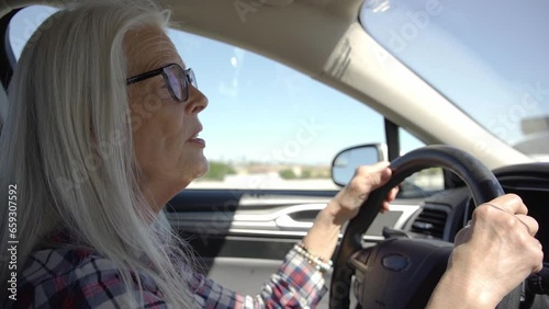 A woman with glasses is driving a car at deserts area during sunshine. Uber driver driving in beautiful place
