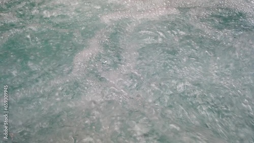 Close up, air bubbles from jacuzzi spa jet in swimming pool.